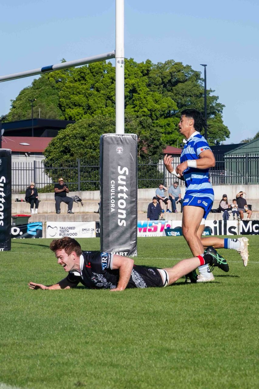 A player slides in for a try beside the posts