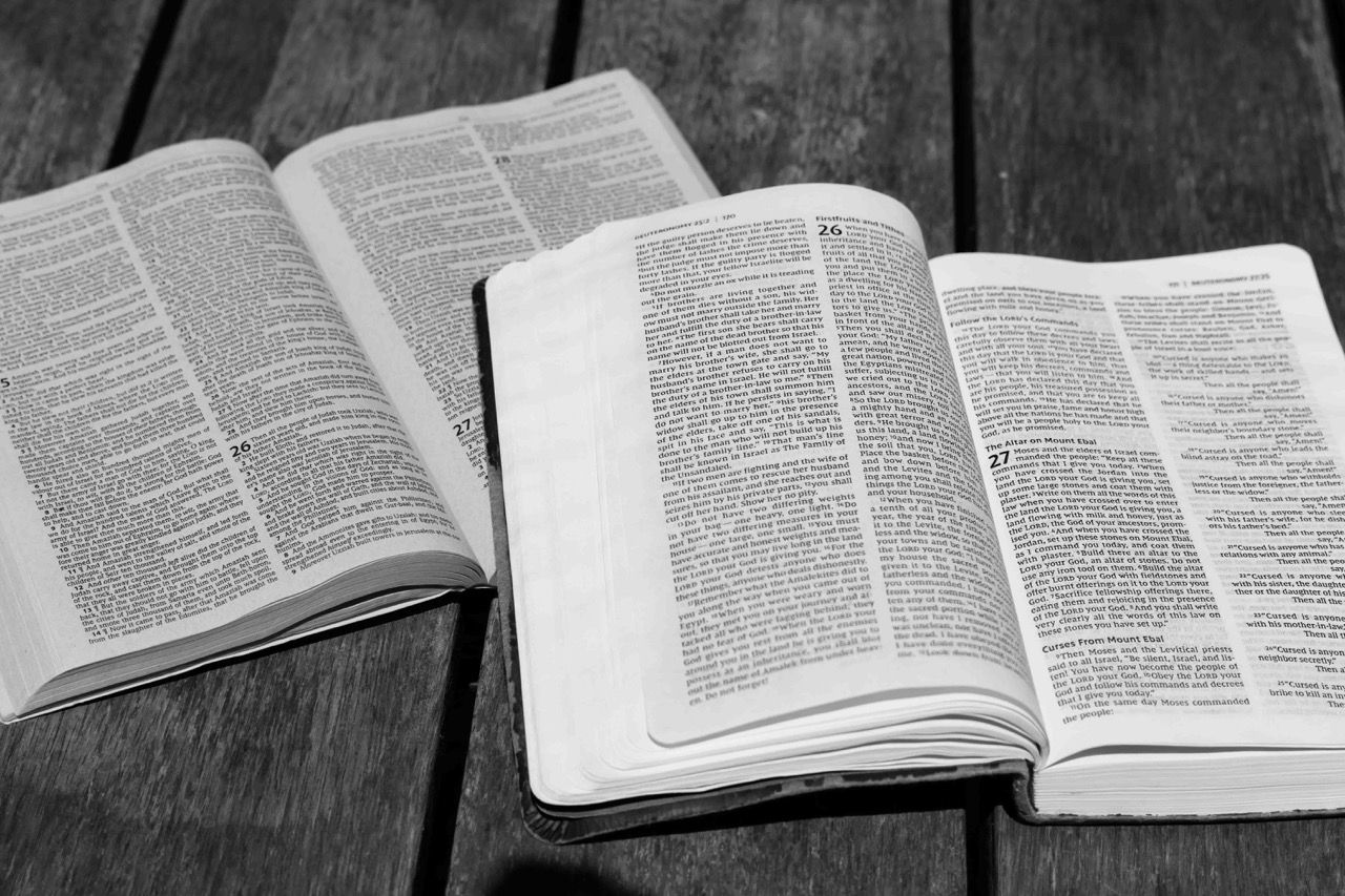 Two open bibles side by side on a wooden table