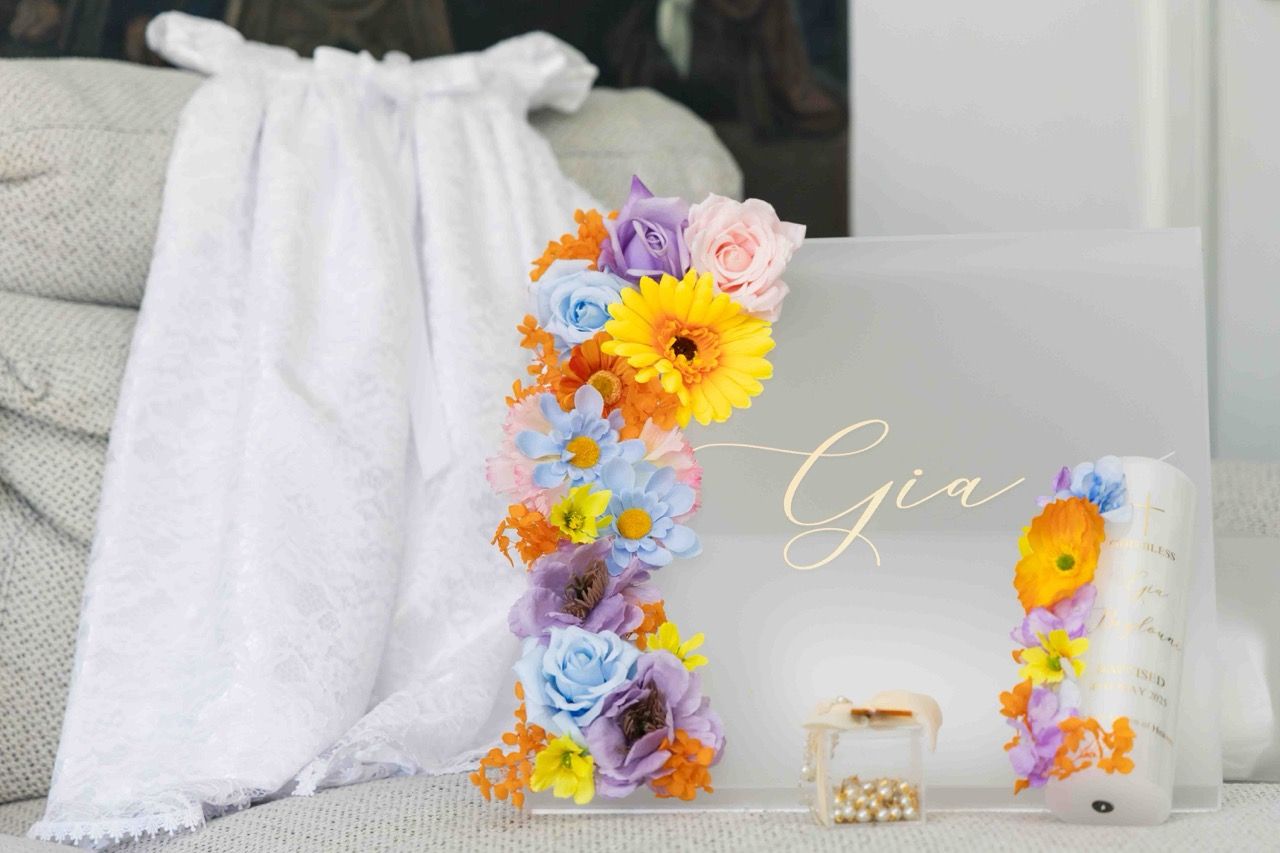 A christening gown beside a floral name sign