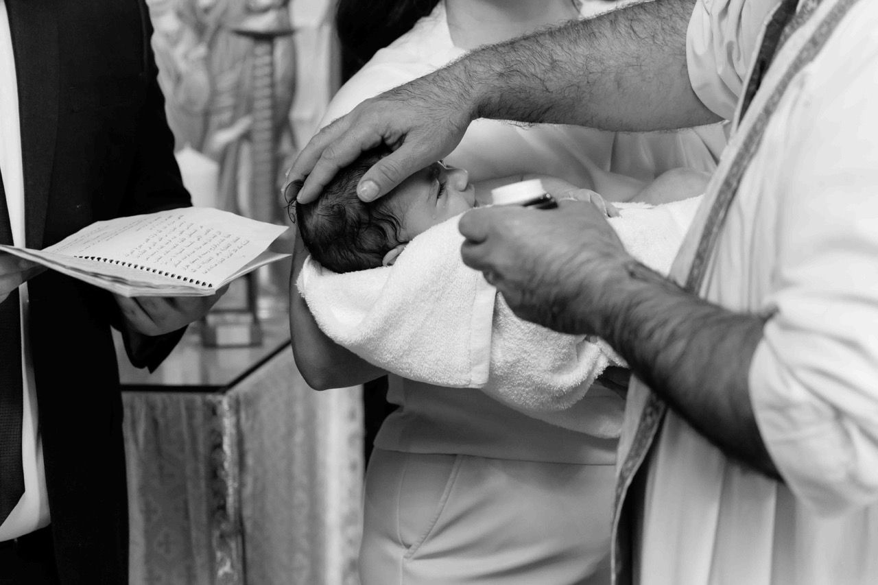A priest’s hands on a baby during the service