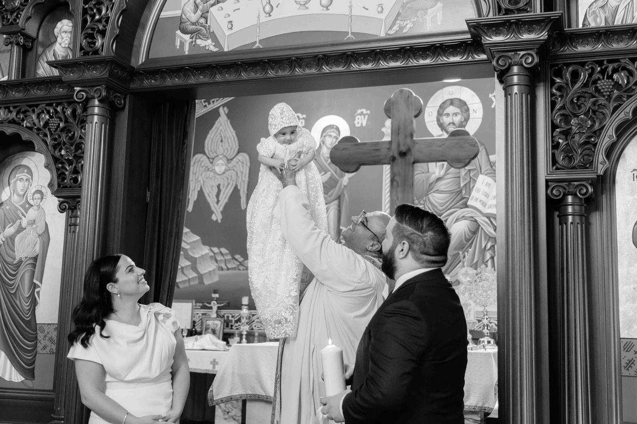 A baby is raised in front of the icons during the service