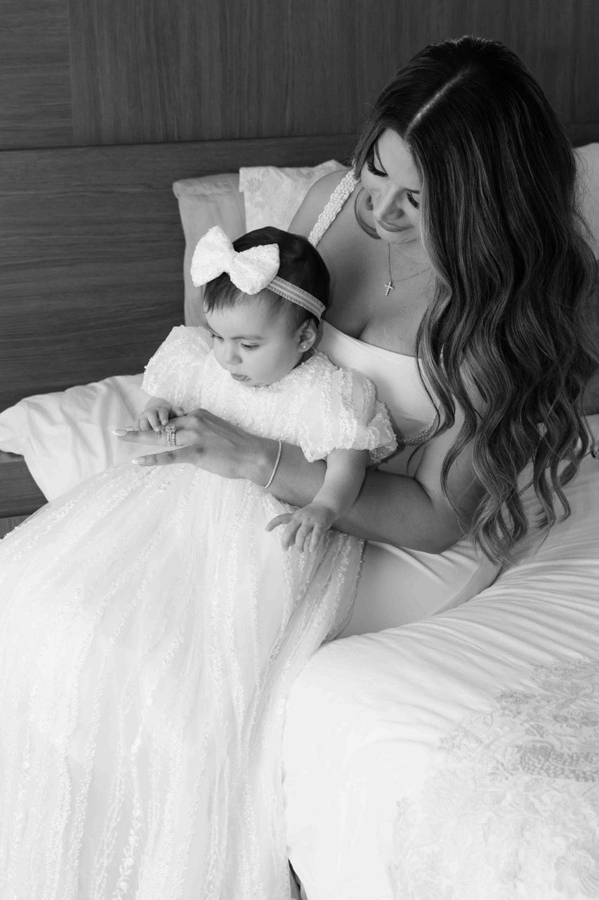 A mother sits with her baby in a white gown