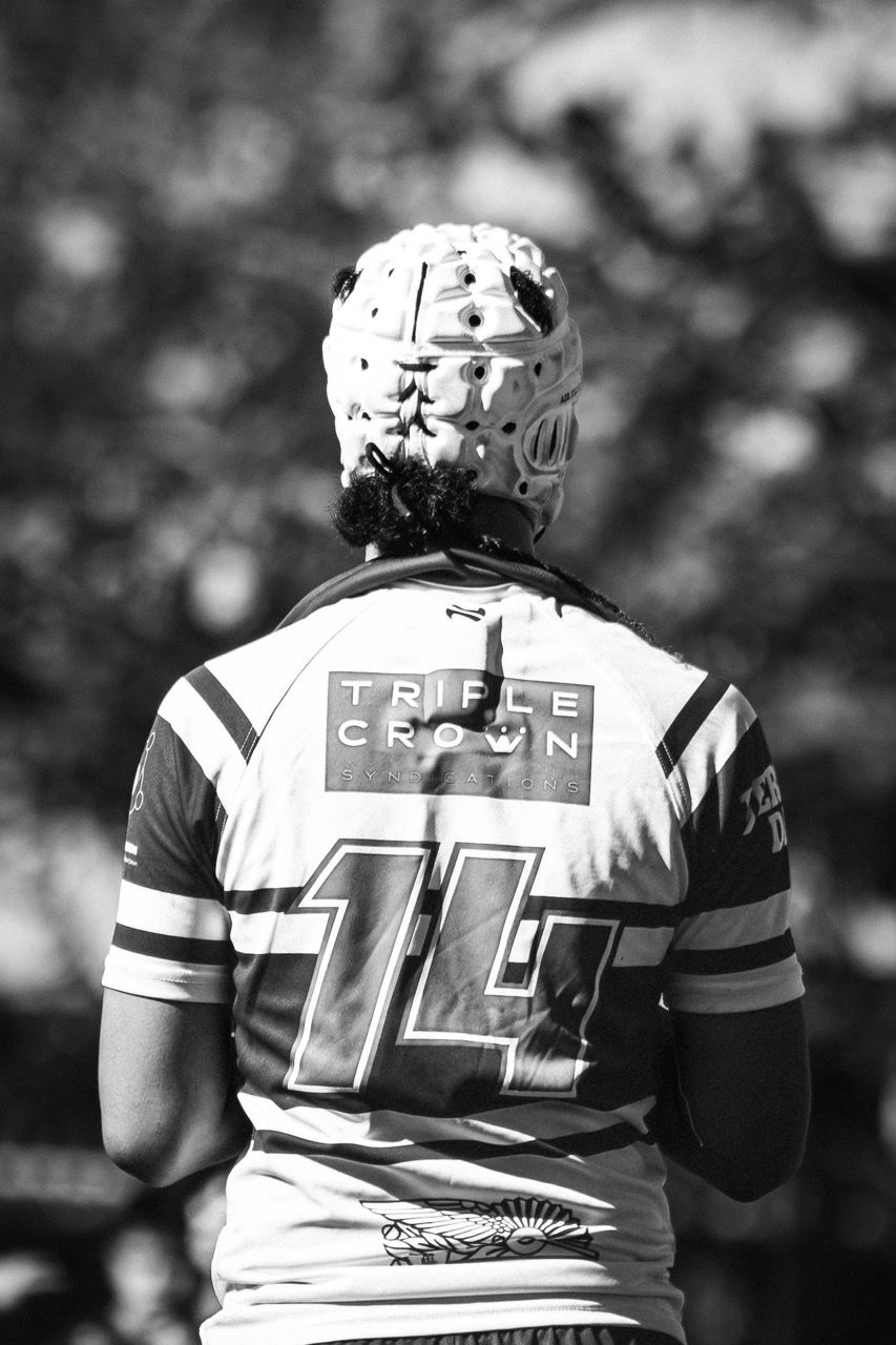 A player in a headguard and number 14 jersey, seen from behind
