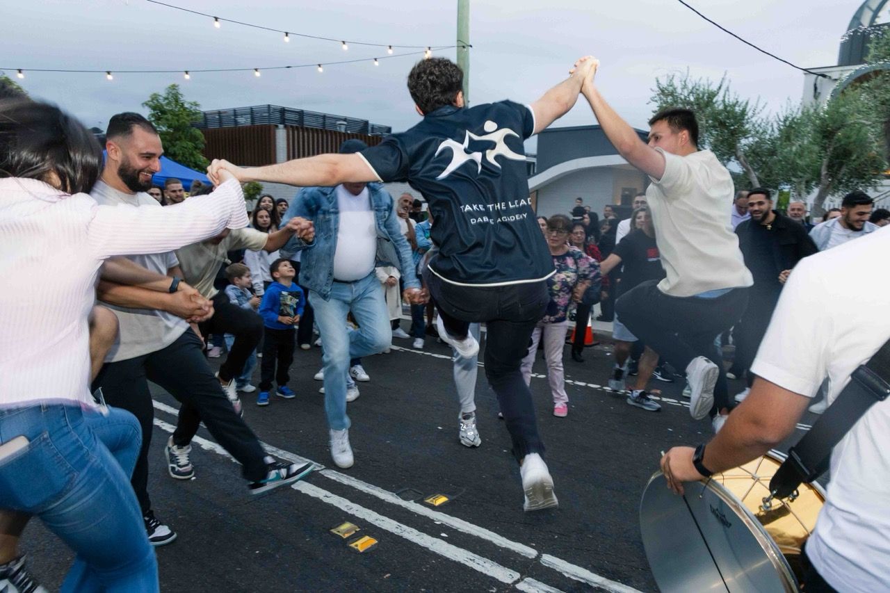 People dance arm in arm in the middle of the street