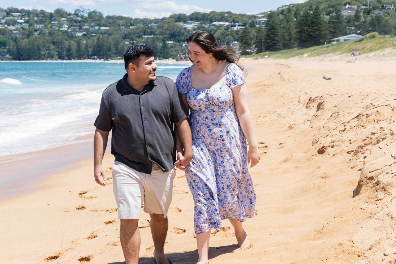 The couple walk hand in hand along the beach