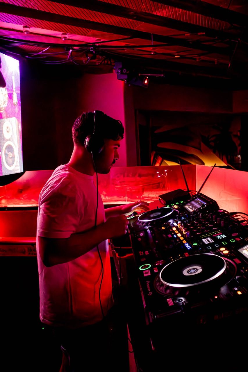A DJ plays under red light in a club