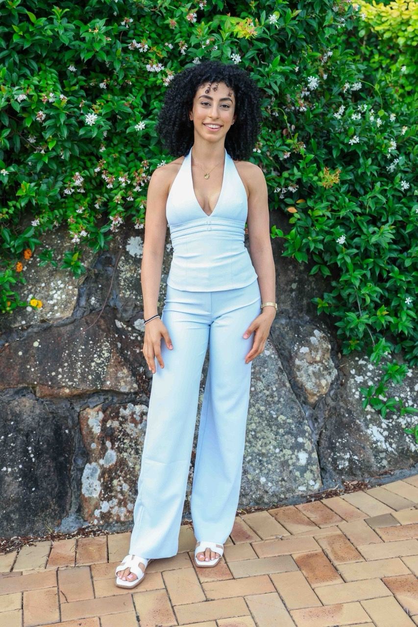 A full-length portrait in white in front of a flowering hedge